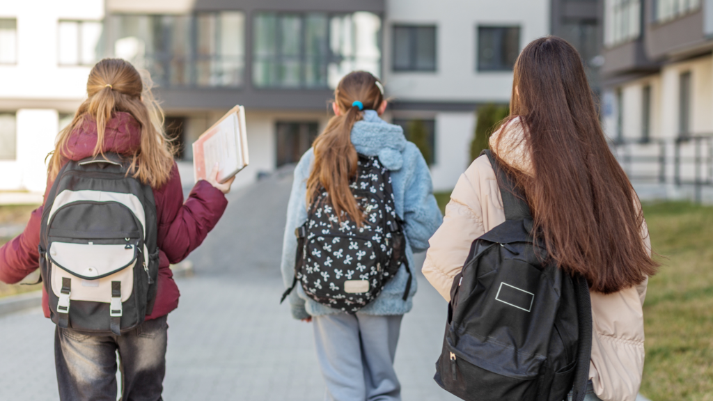 A group of three kids walking to school with backpacks