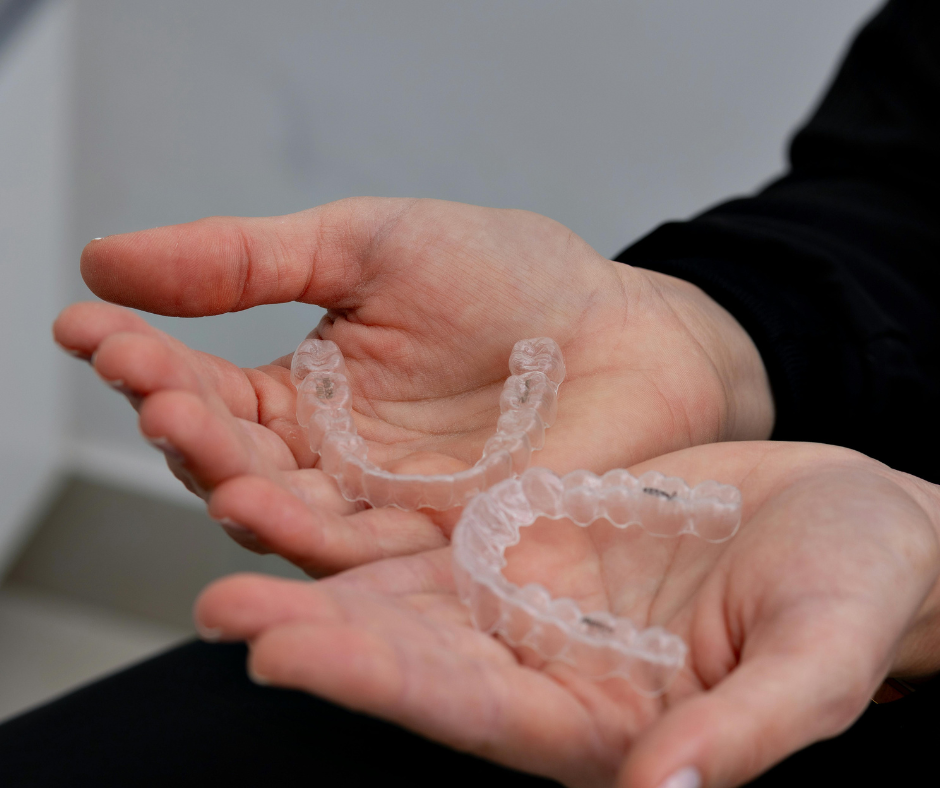 Dos manos sostienen un juego de alineadores transparentes