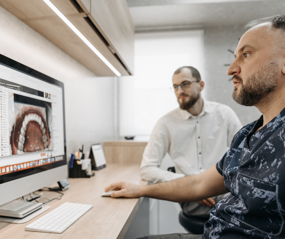 Two men look at scans of a patient’s teeth