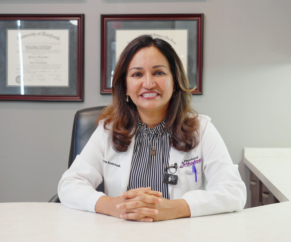 Una ortodoncista sonriente sentada en su escritorio.