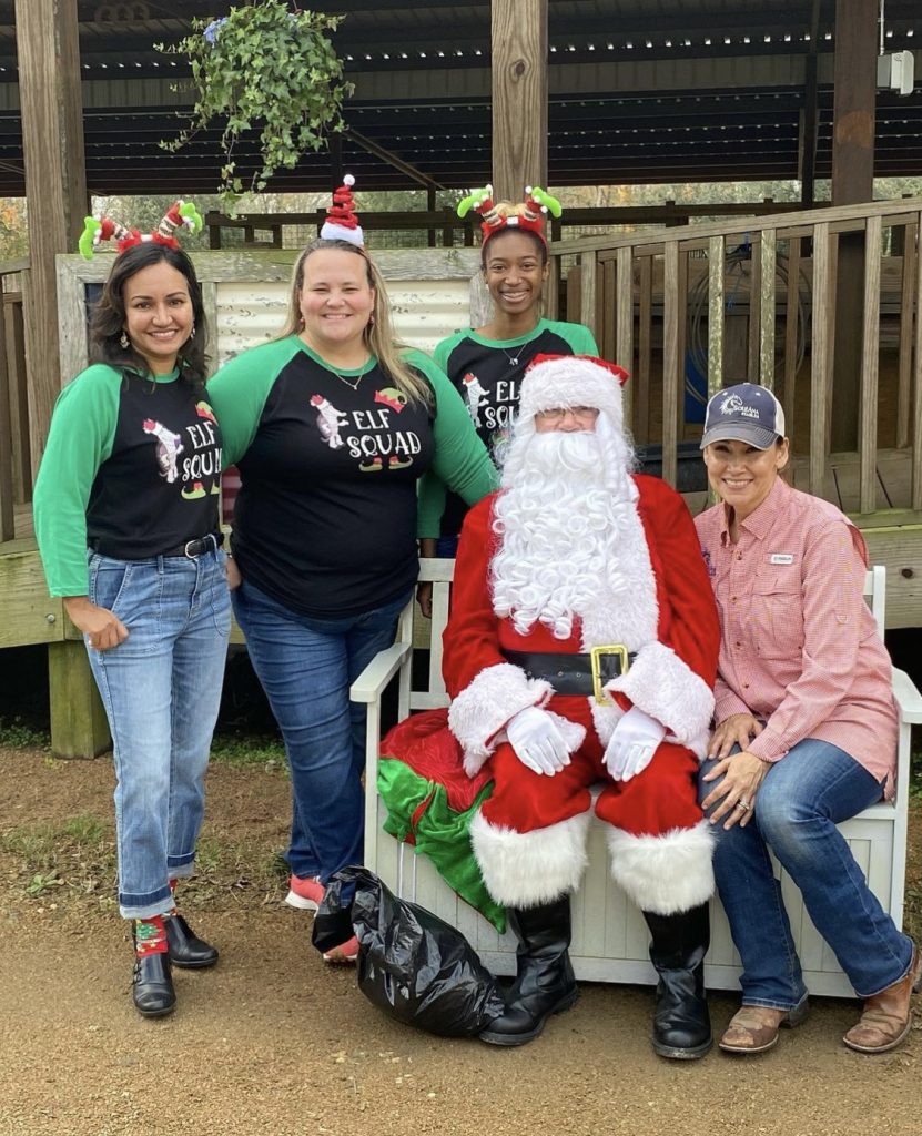 La Dra. Sheela Kudchadker, de Pearland Orthodontics, posa junto a voluntarios y una persona vestida de Papá Noel en una recaudación de juguetes.
