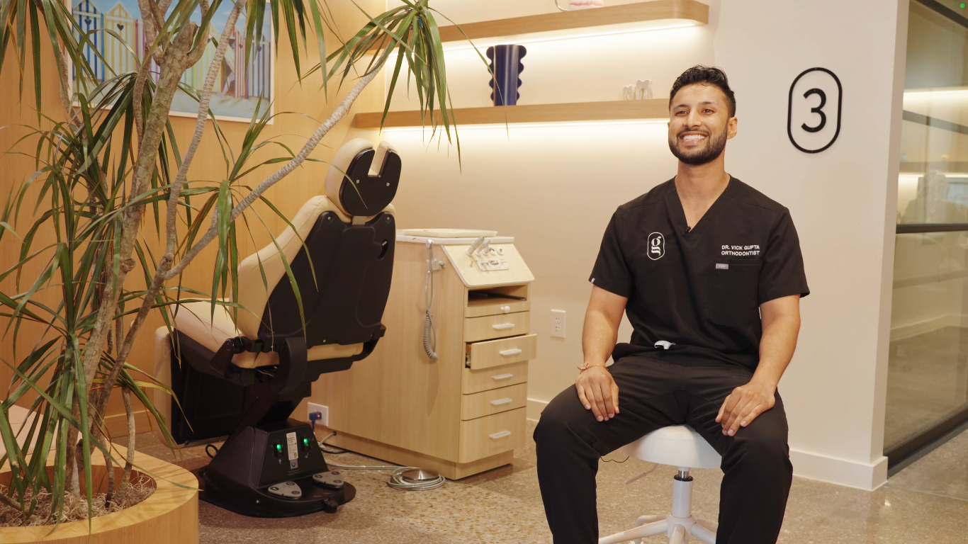 Vick Gupta, a smiling orthodontist sits in a modern orthodontic practice