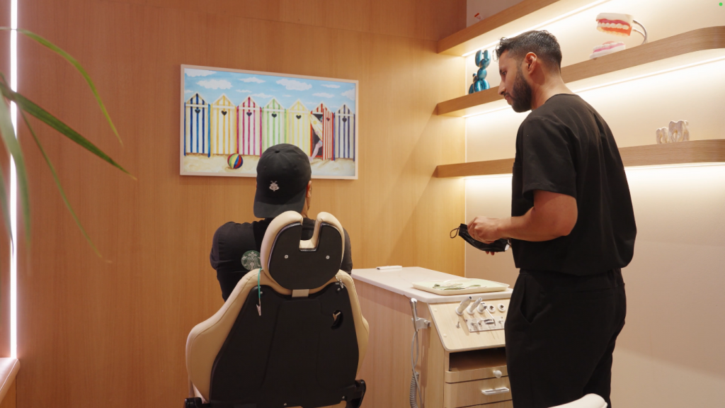 The view from the back of a patient sitting in an orthodontic chair and his orthodontist