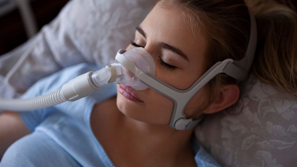 Una mujer duerme con una máquina de presión positiva en las vías respiratorias para tratar la apnea del sueño